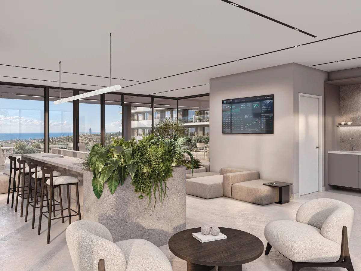 Coworking lounge with armchairs, planting and desks beside full-height windows.